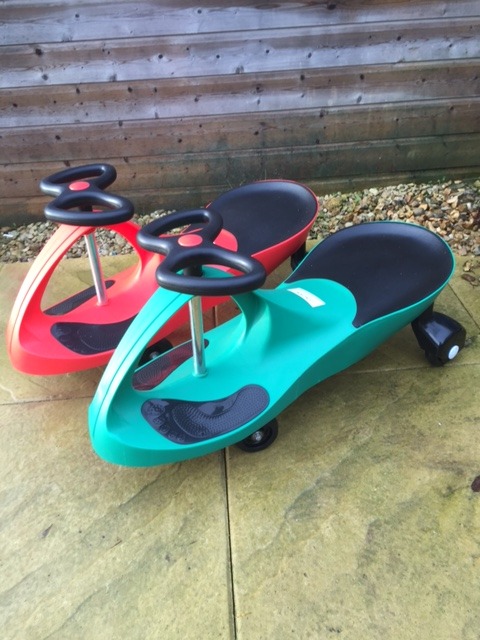 A pair of scooter trike ride-ons, one red and one blue